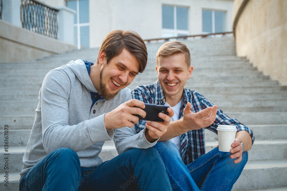 Two friends looking at smartphone laughing together