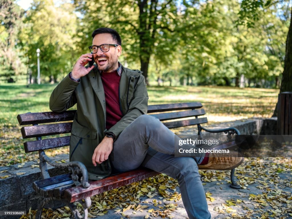 Person sitting on park bench texting smiling